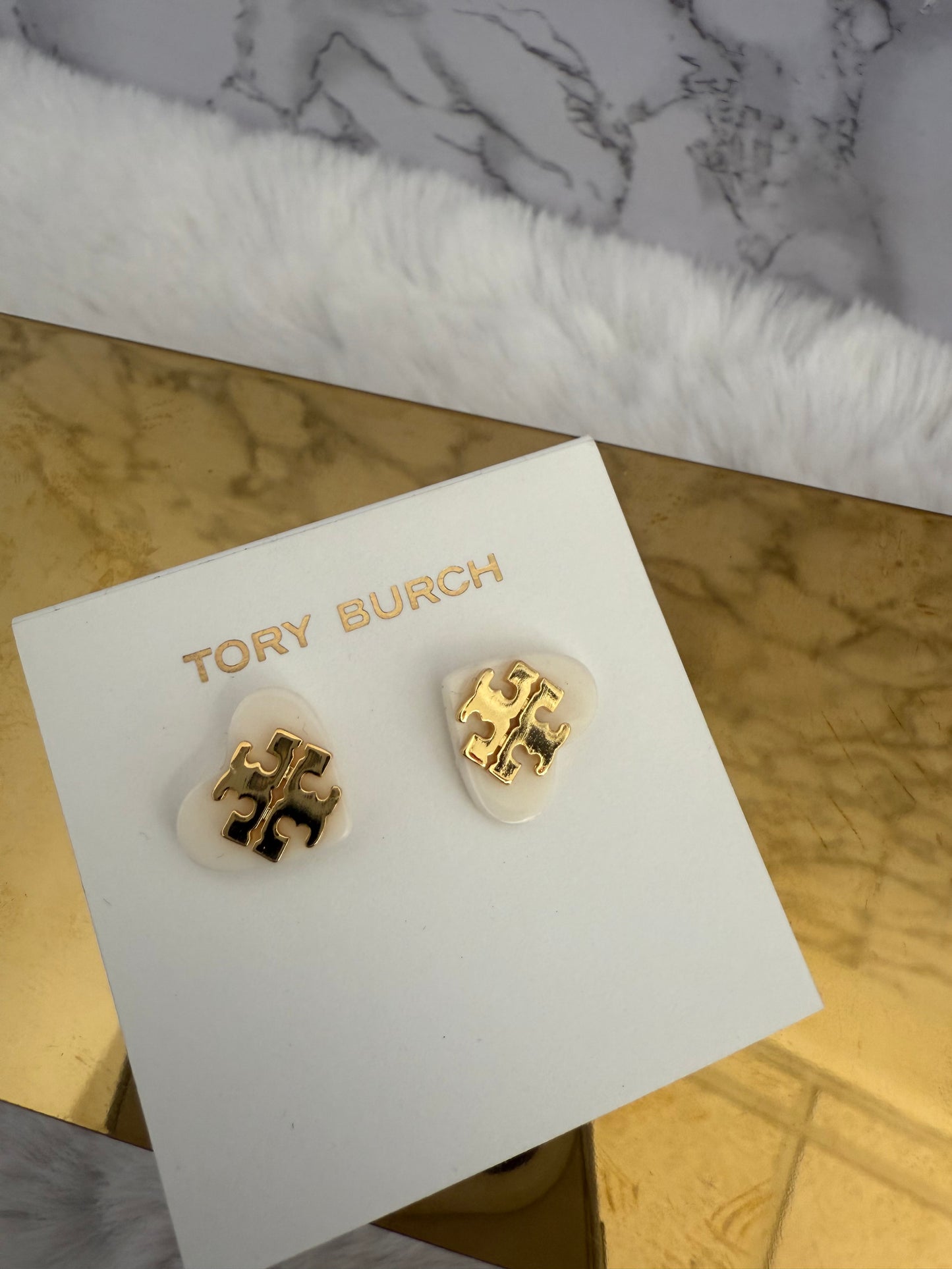 Aretes marca Tory Burch sobre corazón blanco